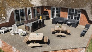 Eine Terrasse im Freien mit Backsteinmauer, Glasüren und einem Grill.