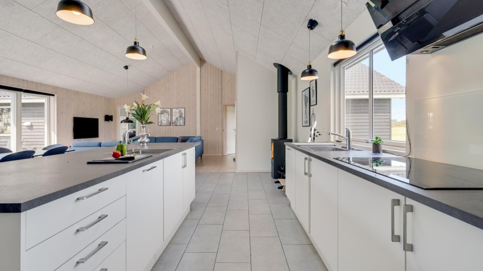 Una cocina moderna con armarios blancos, una isla grande con pileta e iluminación colgante.
