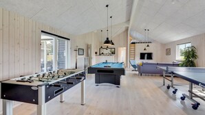 Et stort, indendørs aktivitetsområde med et bordfodboldbord, et billardbord og et bordtennisbord.