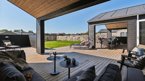 Patio esterno con pavimento in legno, zona relax coperta e area barbecue.