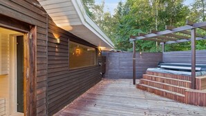 Una terraza de madera con un pérgola y escalones que conducen a una zona de estar.