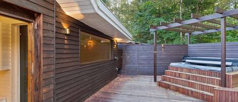 A wooden deck with a pergola and steps leading to a seating area.