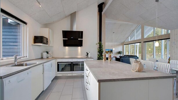Een moderne keuken met een centraal eiland, inbouwapparatuur en grote ramen.