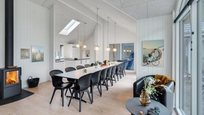 A modern dining area with a long table, black chairs, pendant lighting, and a visible fireplace. - VillaVilla 513 - Marielyst, Lolland/Falster/møn (Væggerløse)