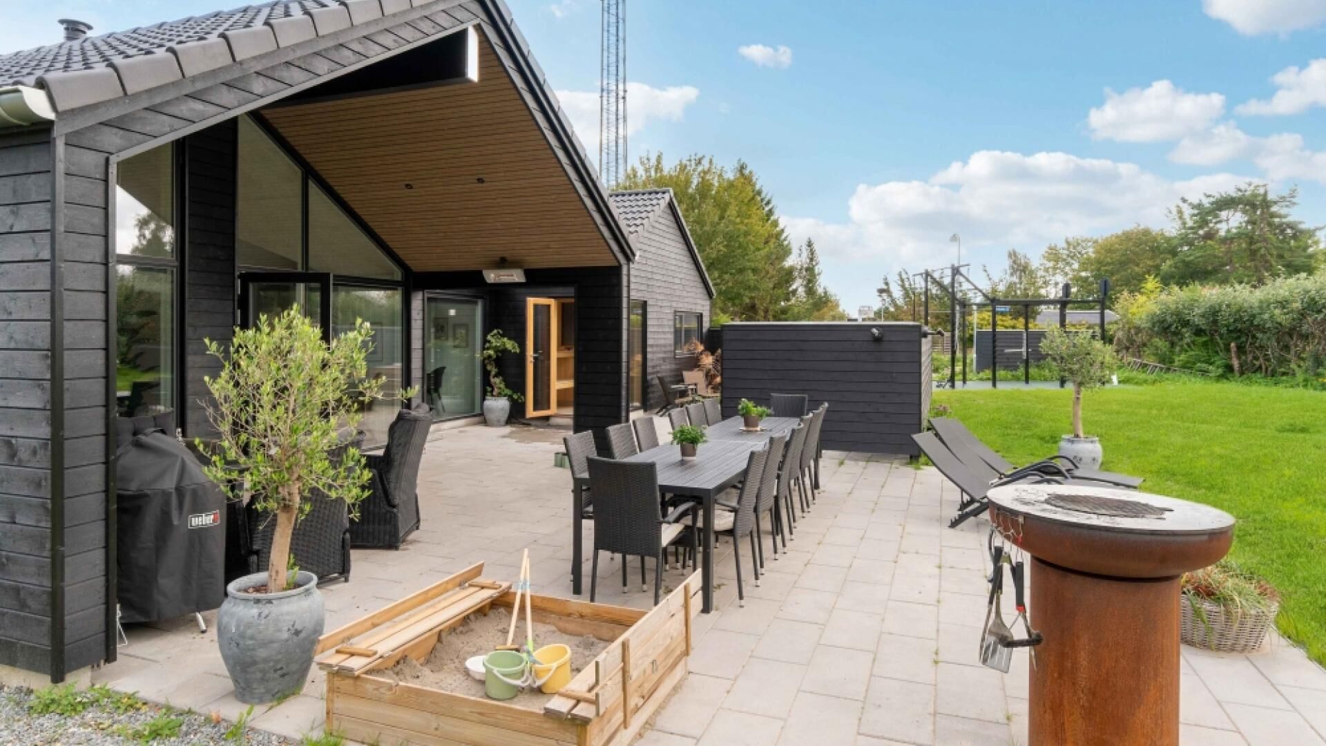 Une maison moderne dotée d’un patio, d’un espace salon extérieur et d’un coin barbecue.
