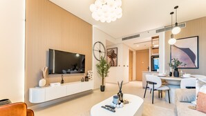 Un salon moderne doté d’un téléviseur à écran plat, d’une console blanche, d’une table basse et d’un coin repas avec une table et des chaises blanches.