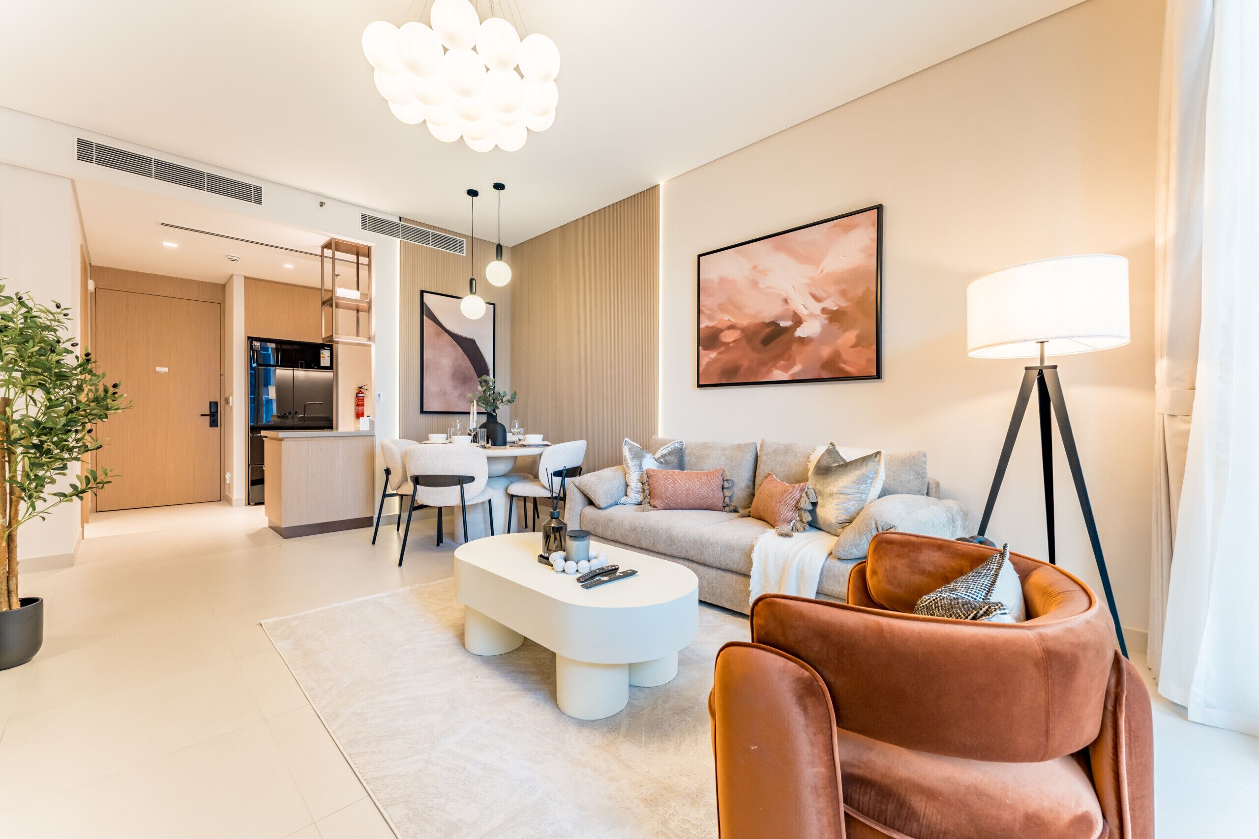 A modern living room with a sofa, coffee table, and a dining area with chairs and a table.