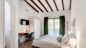 A bedroom with a bed, a desk, a chair, a TV, and a window with curtains. - Near the lake and the center (FLORIDA ASCONA Room 09) (Ascona)