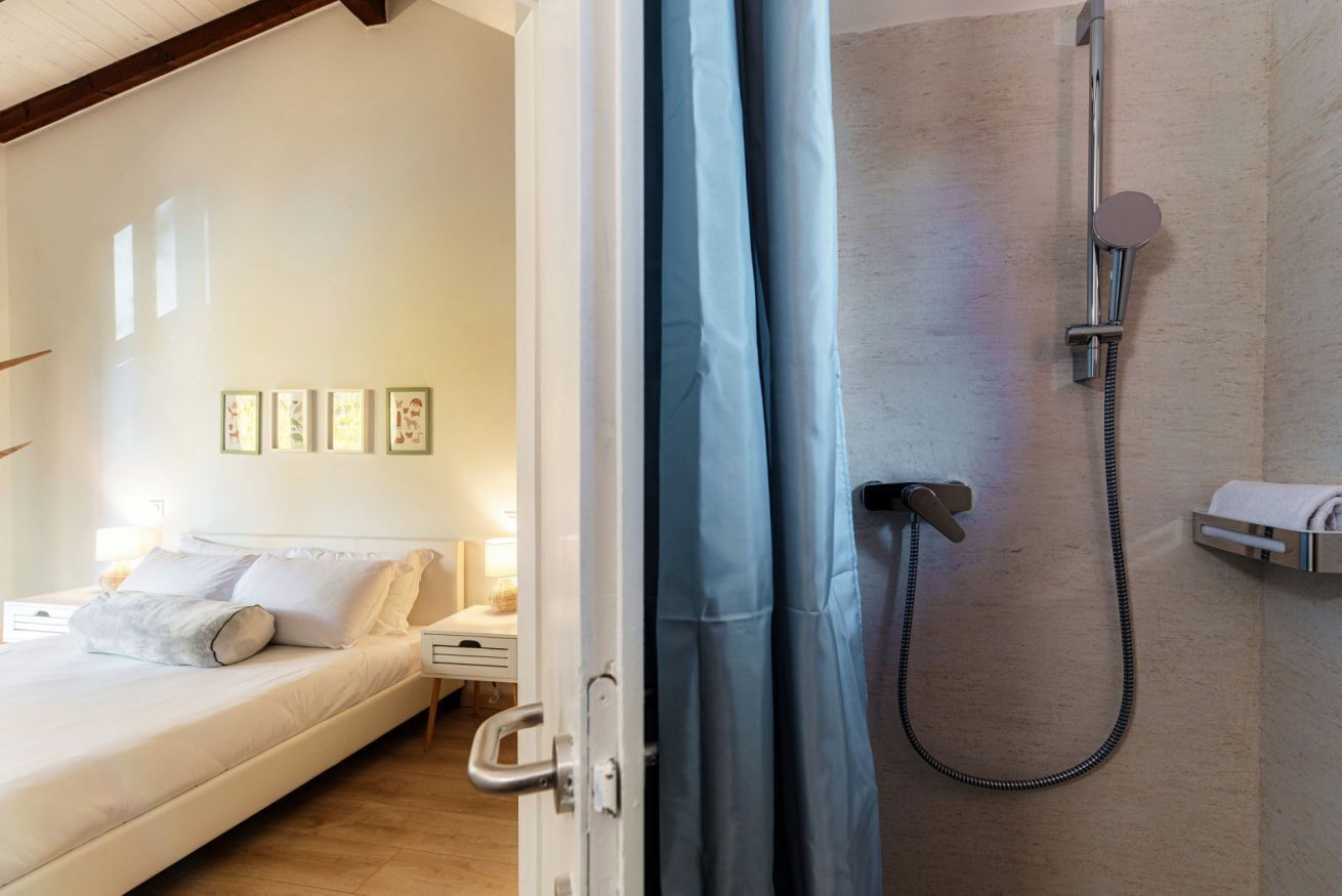 Une chambre à coucher comprenant un lit, une table de chevet, une commode, une douche et un porte-serviettes.