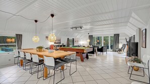 Una habitación amplia con mesa de billar, chimenea y mesa de futbolín.