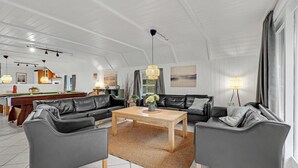 Un salón amplio con mesa de billar, sofás de cuero y una mesa de centro de madera.