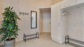 Un baño moderno con pared de madera, una planta en maceta, un espejo y un vestidor.