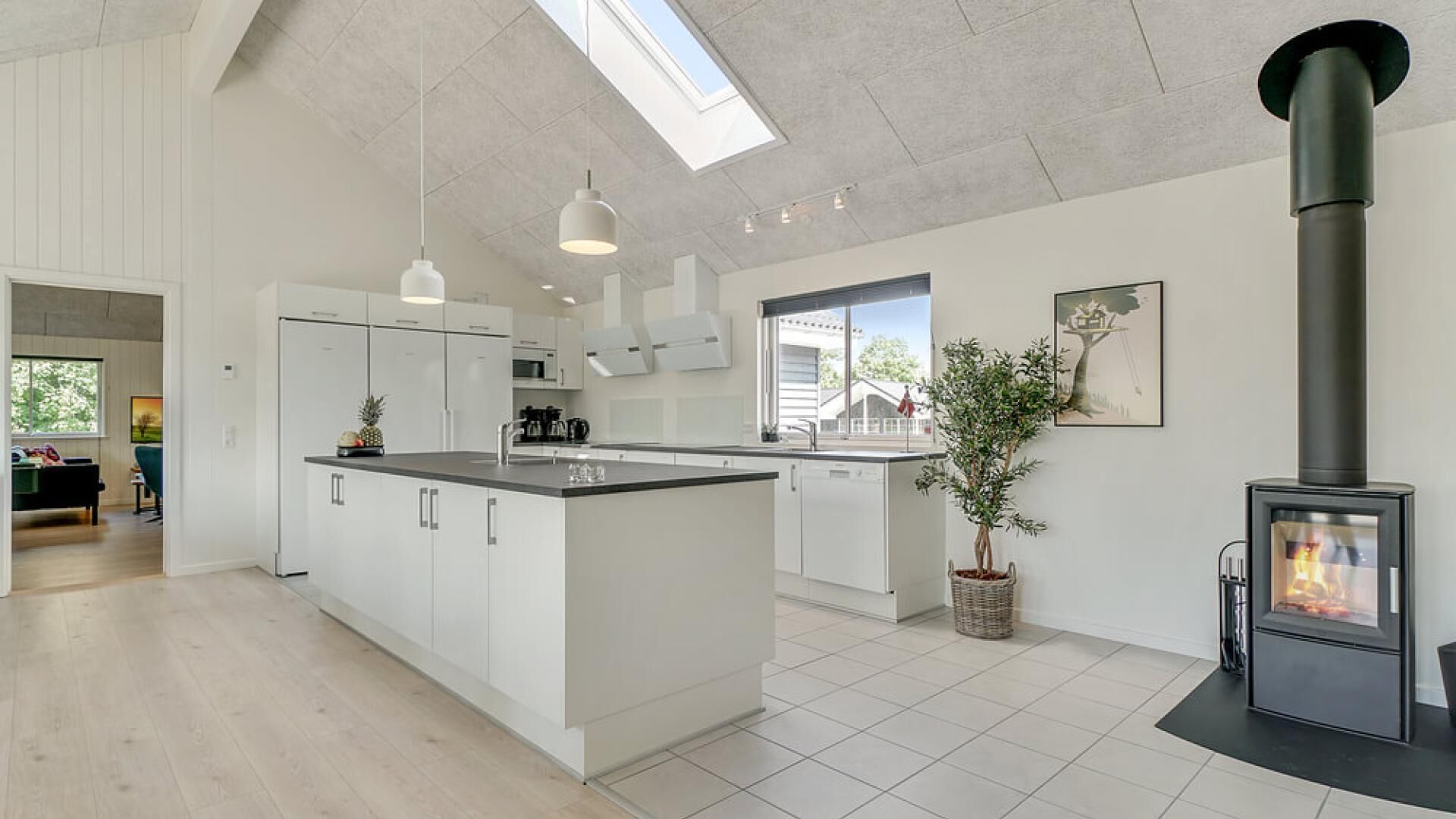 A modern kitchen with a central island, white cabinetry, and a black stove.