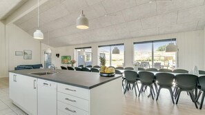 A spacious kitchen with a large island, modern pendant lights, and a view of the outdoors.