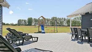 An outdoor patio with lounge chairs, a children's play structure, and a covered seating area. - VillaVilla 343 - Marielyst, Lolland/Falster/møn (Væggerløse)