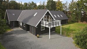 Une maison à deux étages avec un toit en pente, une véranda et une allée gravillonnée.