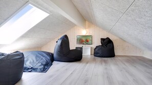 Habitació d'estil loft amb sostre inclinat, dos seients de bossa, un televisor de pantalla plana i un quadre a la paret.