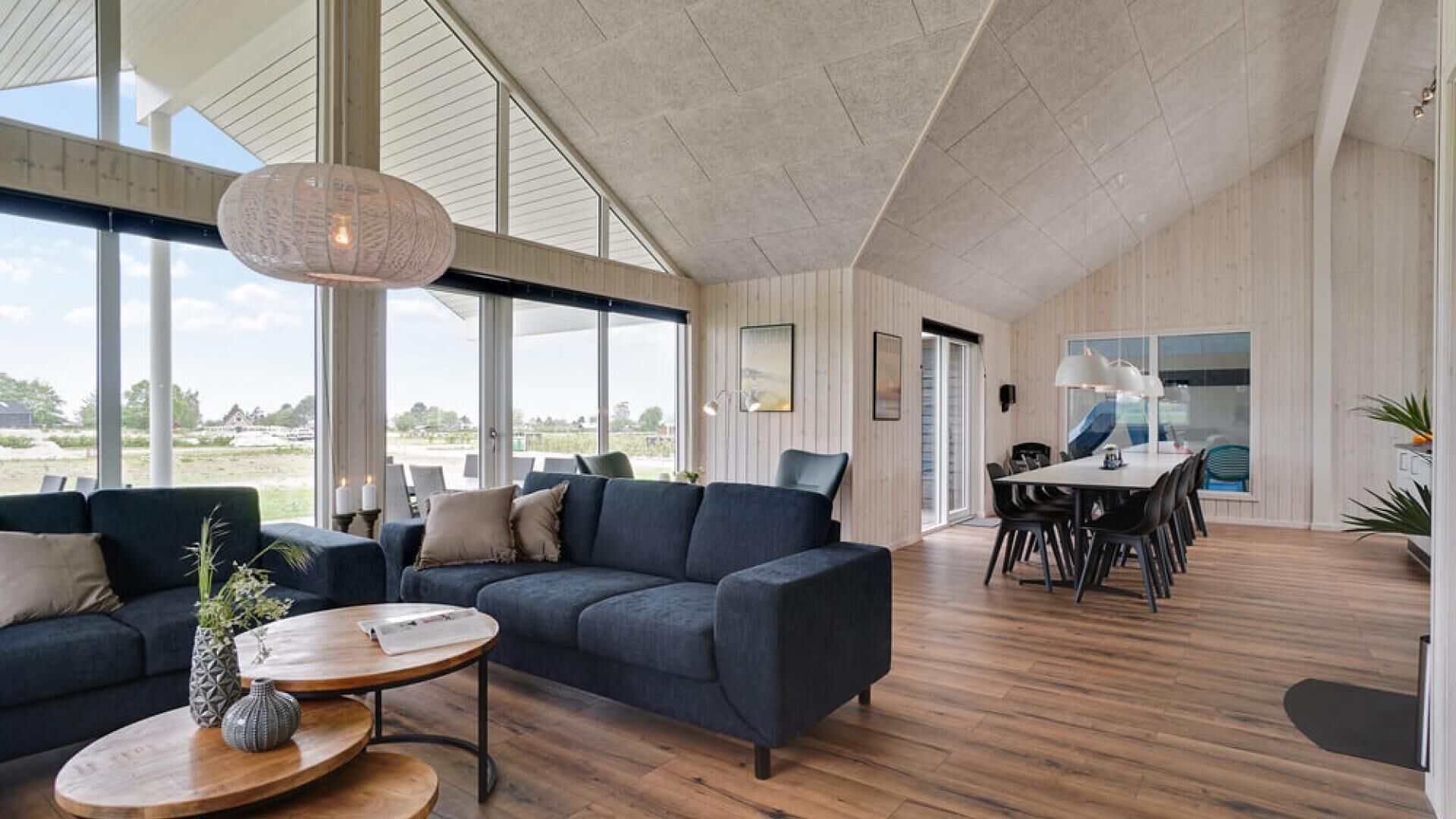 A spacious living room with a large sofa, a coffee table, and a dining area with a table and chairs.