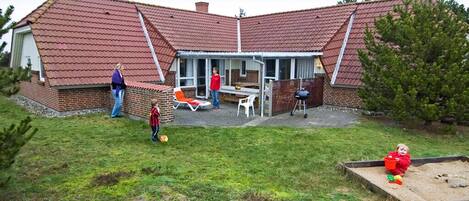 A house with a red-tiled roof, a brick exterior, and a covered patio area.