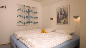 Ein Schlafzimmer mit einem Bett, einem Teddybären, einem Gemälde und einer Wandleuchte.