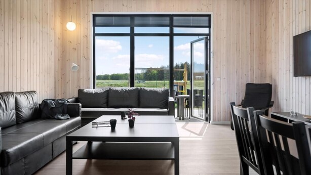 Una sala de estar moderna con un sofá de cuero, una mesa de centro y un televisor montado en la pared.