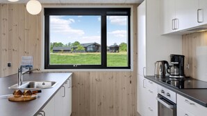 Una cocina moderna con un ventanal amplio, electrodomésticos de acero inoxidable y armarios de madera.