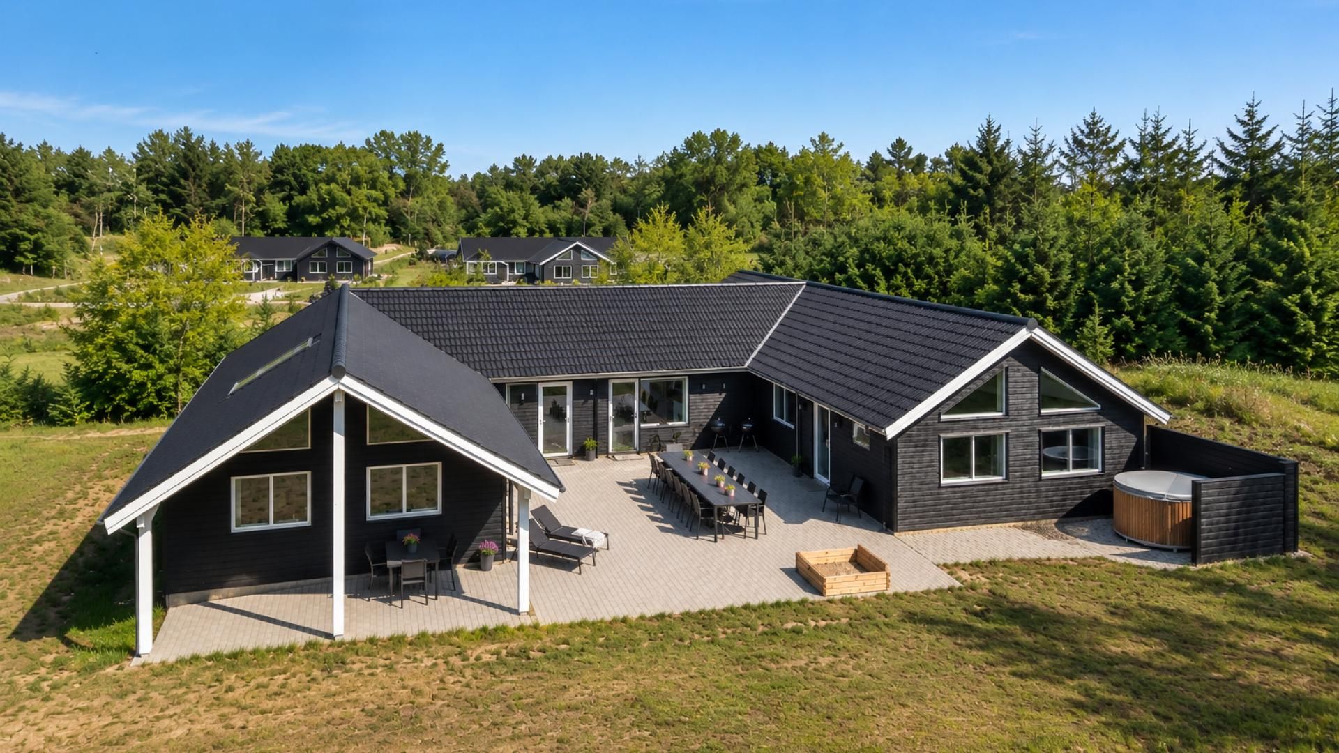 Een modern huis met twee verdiepingen, een terras, grote ramen en een verzorgd gazon.