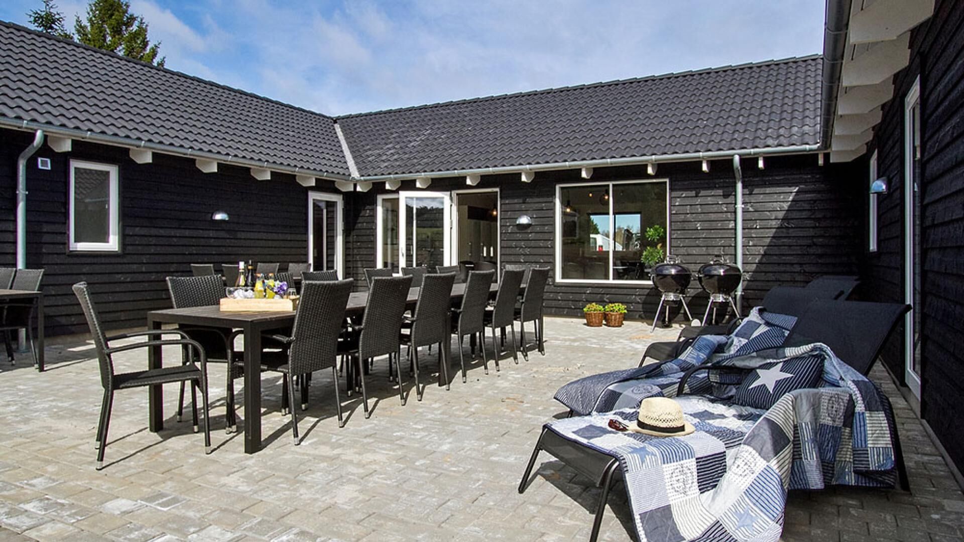 Un espace patio aménagé avec du mobilier d’extérieur, un barbecue et un coin salon abrité.