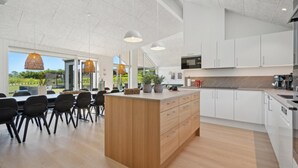 Une cuisine moderne avec des meubles blancs, un îlot central en bois et des luminaires suspendus.