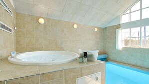 A modern bathroom with a large bathtub, a shower area, and a window providing natural light. - VillaVilla 302 - Saksild, Østjylland (Odder)