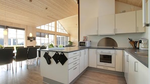 A modern kitchen with white cabinets, a built-in oven, and a large island with a microwave. - VillaVilla 302 - Saksild, Østjylland (Odder)
