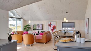 A spacious living area with a large dining table, comfortable seating, and a view of the outdoors.