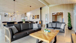 A modern interior with a wooden ceiling, black leather sofas, a wooden coffee table, and a fireplace. - VillaVilla 264 - Kegnæs, Sydjylland (Sydals)