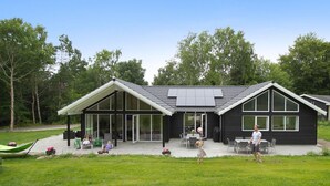 Una casa moderna con porche cubierto, ventanas amplias y césped.