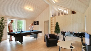 Un interior de madera con dos mesas de billar, un sofá y una escalera.