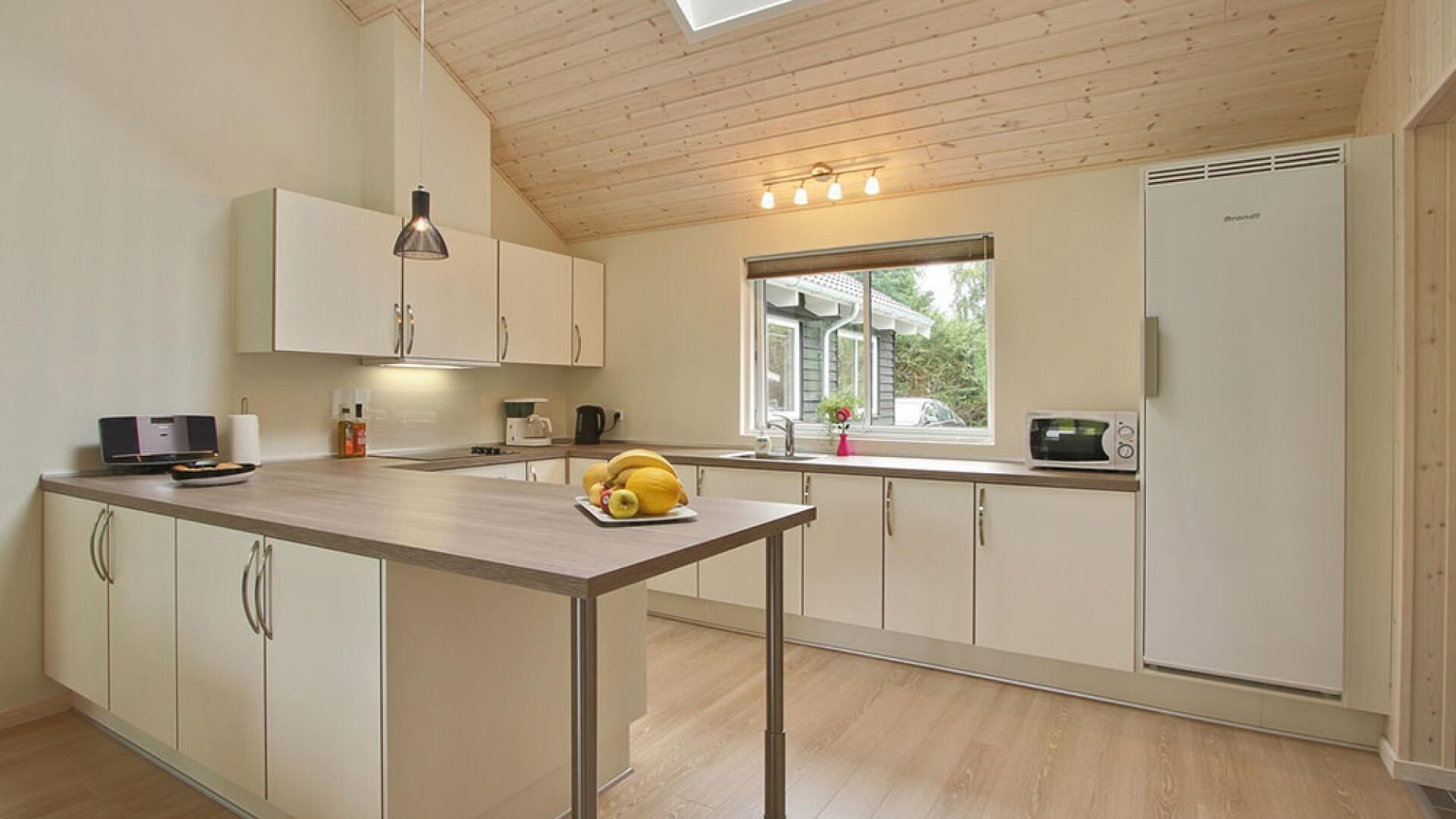 A modern kitchen with a central island, a built-in oven, and a window providing natural light.