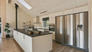 Cozinha moderna com ilha central, eletrodomésticos de aço inoxidável e uma grande janela que permite entrada de luz natural.