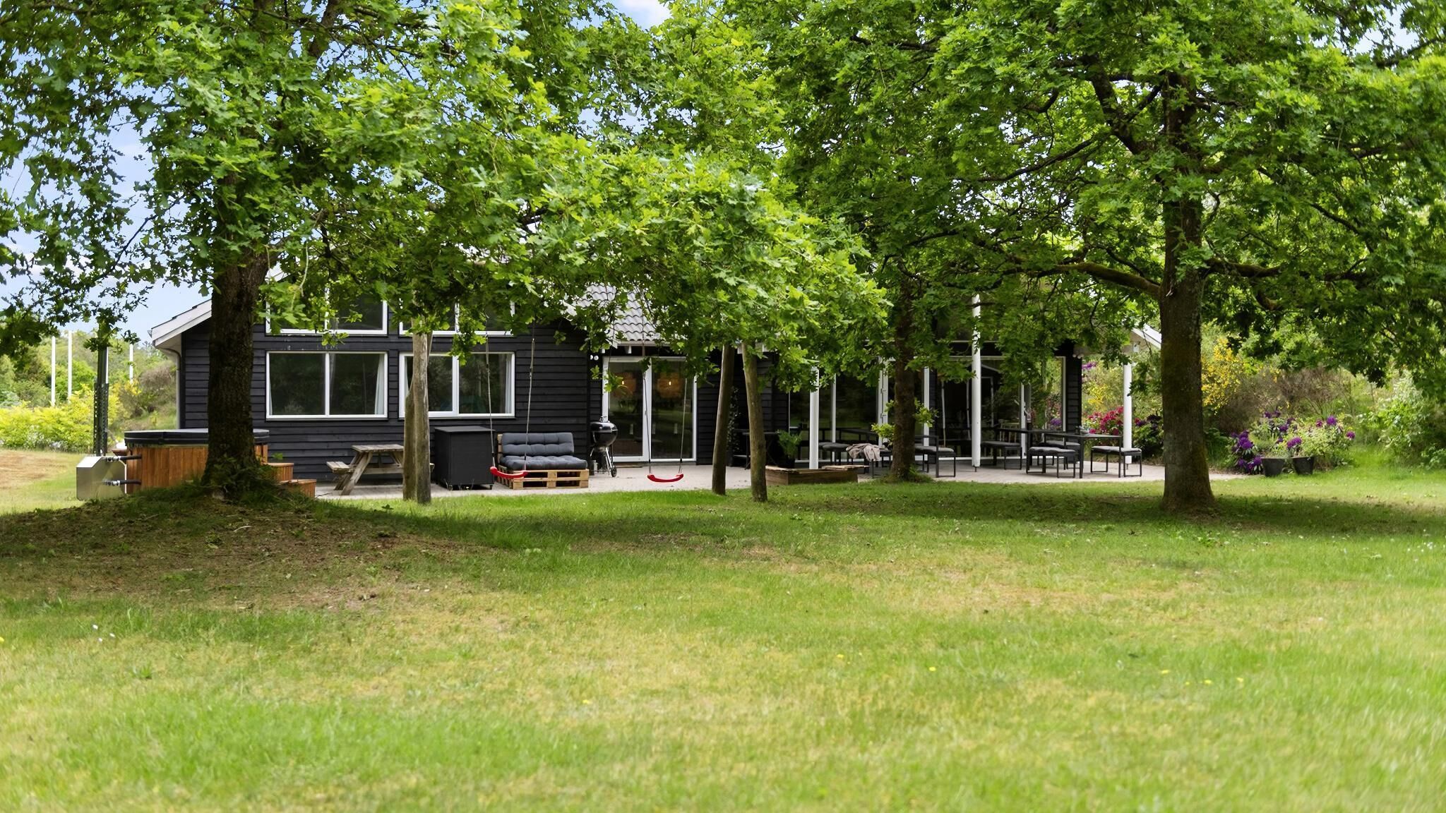 Ein modernes Gebäude mit einer Terrasse, Sitzgelegenheiten im Freien und einem Grill.