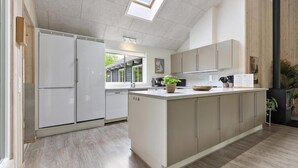 Una cocina moderna con una isla central, electrodomésticos integrados y vistas al exterior.