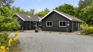 A two-story black building with a number 19 sign, a gravel driveway, and surrounding greenery. - VillaVilla 313 - Henne Strand, Vestjylland (Henne)