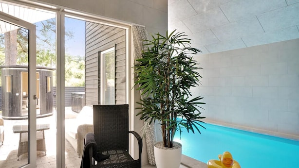 Área de piscina com cadeira, planta em vaso e um pato inflável amarelo.