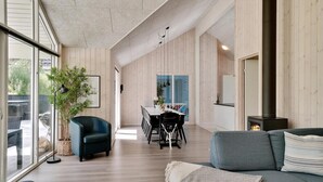 Uma sala de estar ampla com uma janela grande, uma mesa de jantar e um sofá.