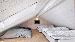A small attic bedroom with a sloped ceiling, a single bed, and a television mounted on the wall. - VillaVilla 315 - Skåstrup Strand, Fyn og øer (Bogense)