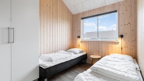 A bedroom with two beds, a small round table, and a window with blinds. - VillaVilla 322 - Skåstrup Strand, Fyn og øer (Bogense)