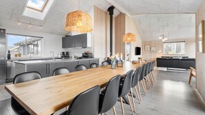 A modern kitchen with a central island, black chairs, and a wooden dining table. - VillaVilla 322 - Skåstrup Strand, Fyn og øer (Bogense)