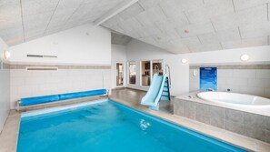 A swimming pool with a slide, a separate hot tub, and a kitchen area visible through an open door. - VillaVilla 322 - Skåstrup Strand, Fyn og øer (Bogense)