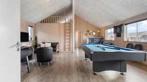 Ein moderner Innenraum mit Pooltisch, Sitzgelegenheit und Bar.