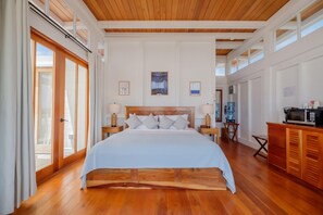 Quarto de hotel com uma cama grande, teto de madeira e vista para o exterior.