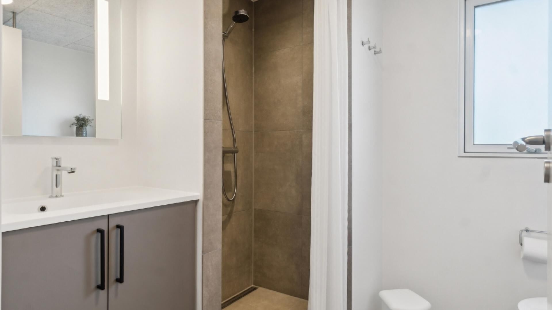 A modern bathroom with a shower, a toilet, and a sink.