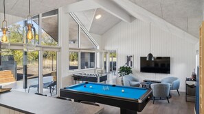 Ein geräumiger Innenbereich mit Billardtisch, Sitzgelegenheiten und Fernseher.
